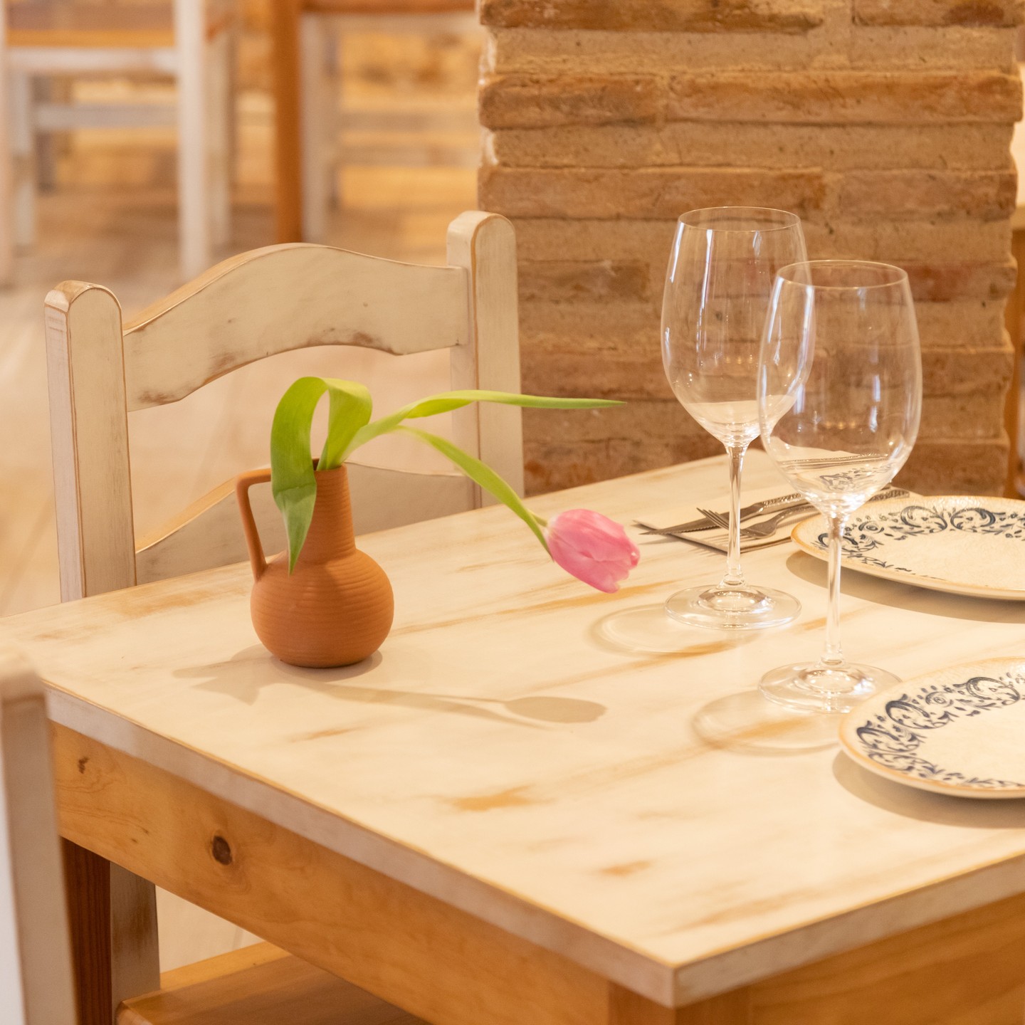 Mesa preparada con jarra de barro y tulipán