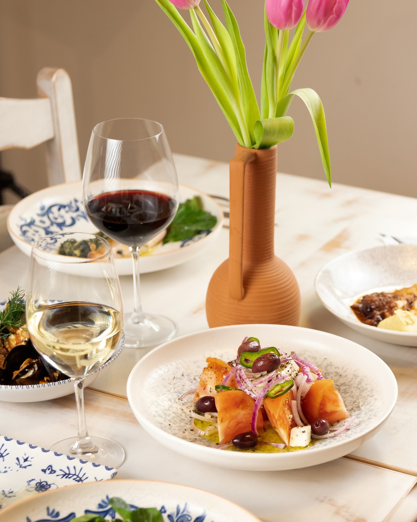 Mesa con ensalada griega, mejillones y vino en El Greco Bistrot